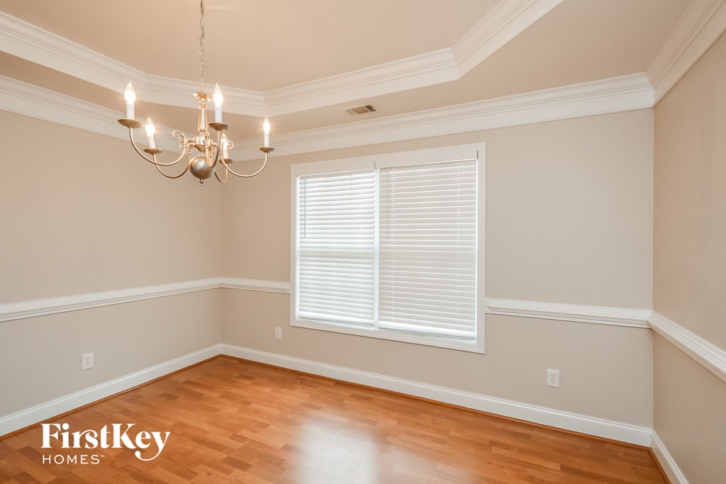 an empty dining room with a chandelier and a window