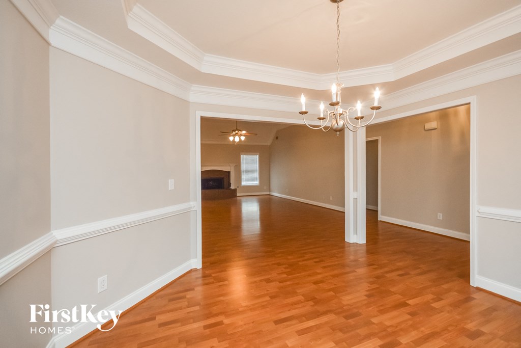an empty living room with wood floors and a chandelier
