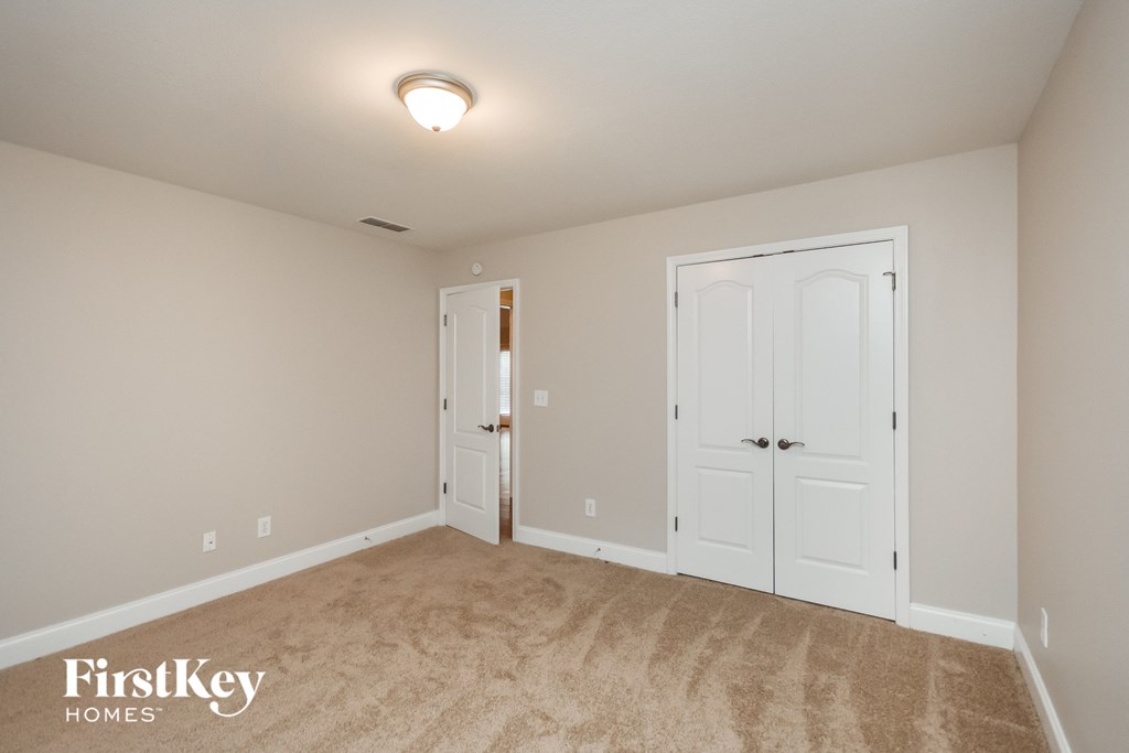 a bedroom with white doors and carpeting and a door to a closet
