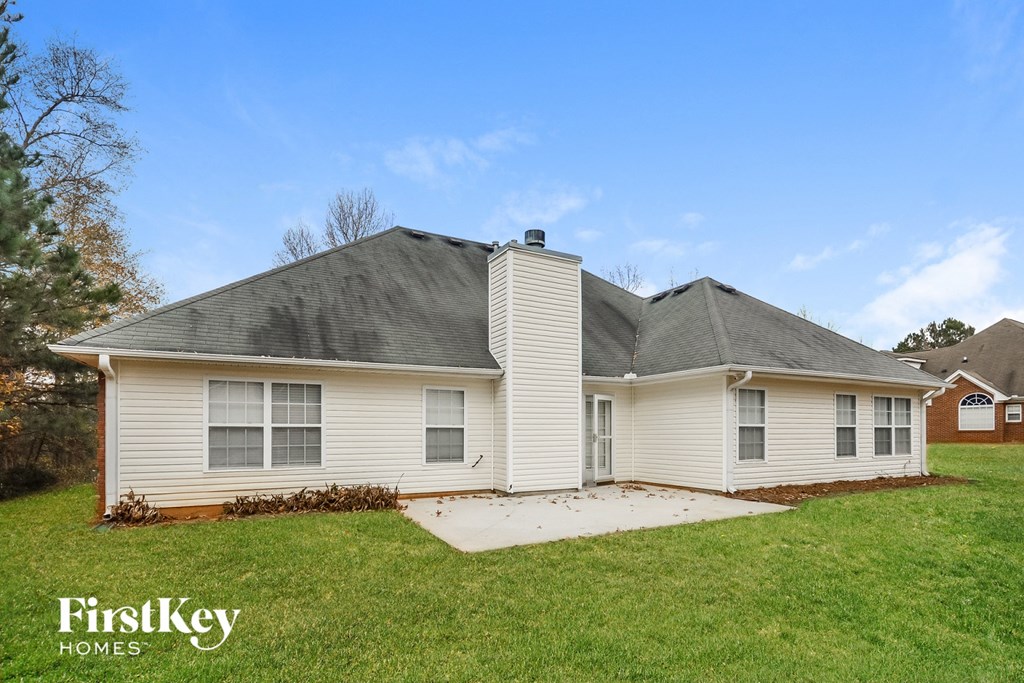 a white house with a gray roof on a grass field