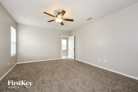 a spacious living room with carpet and a ceiling fan