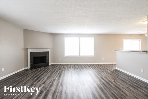 A spacious room with a fireplace and wood flooring.