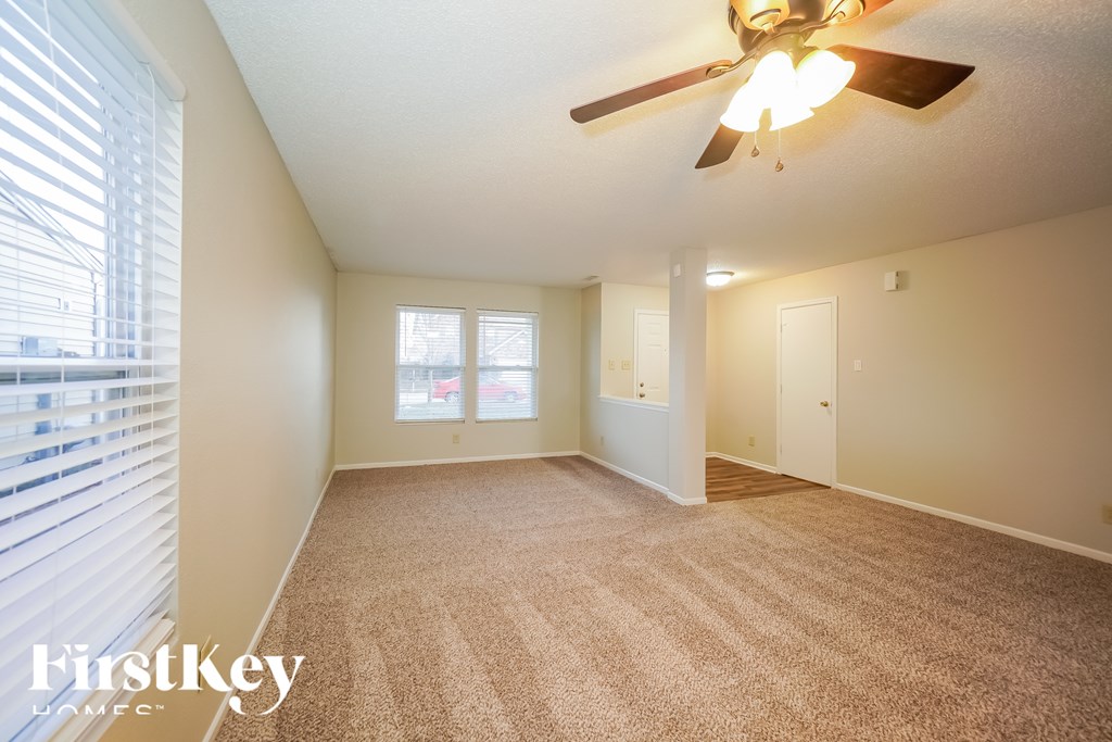 A room with a carpet floor and a ceiling fan.