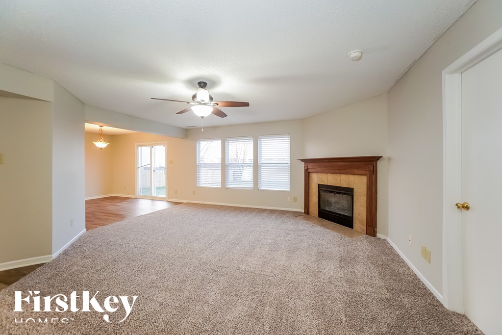A spacious living room with a fireplace and a ceiling fan.