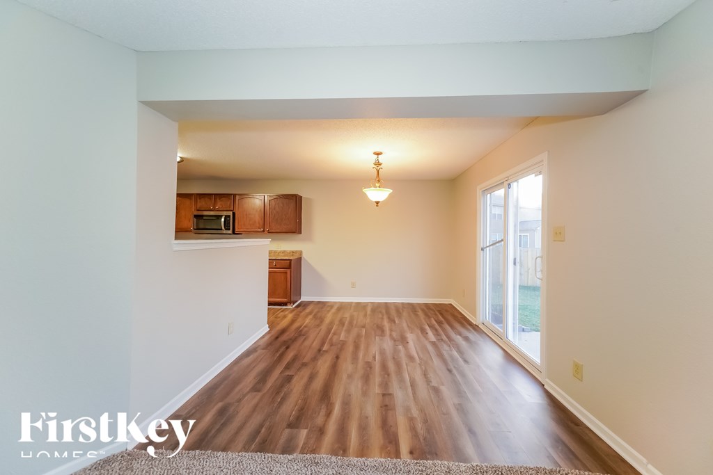 A spacious room with wooden flooring and a window letting in natural light.