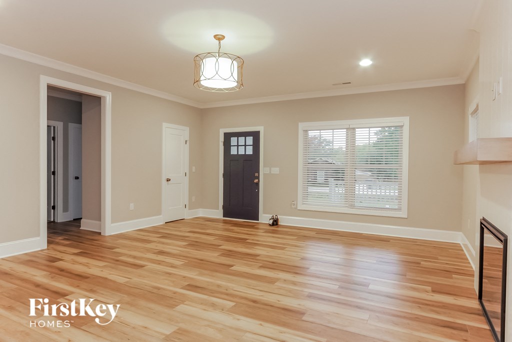 an empty living room with a hardwood floor and a door to a hallway