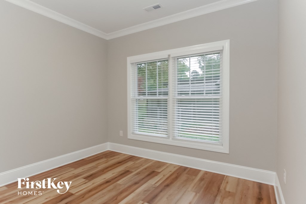 the second bedroom has a hard wood floor and a large window