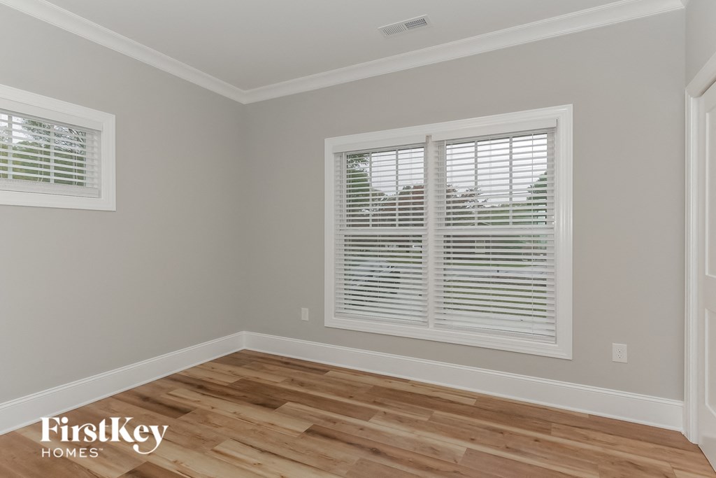 the second bedroom has a hardwood floor and two windows
