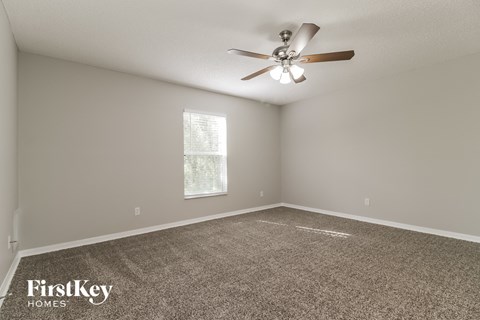 the spacious living room has carpet and a ceiling fan