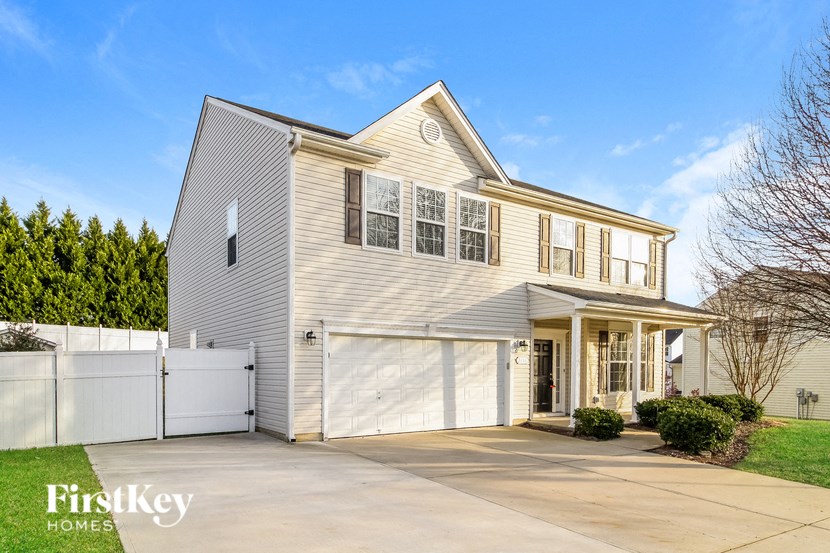 a gray house with a white garage door and a white fence