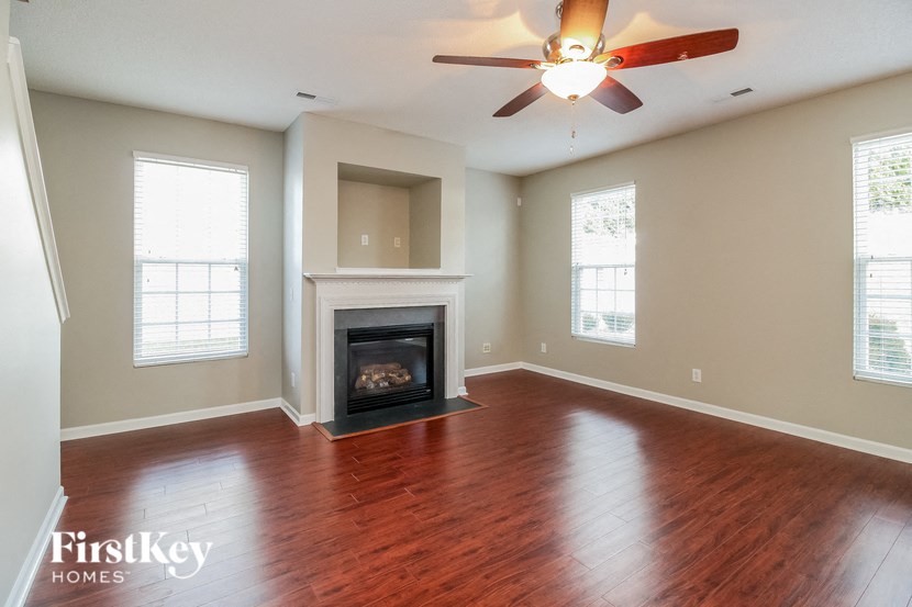 an empty living room with a fireplace and a ceiling fan