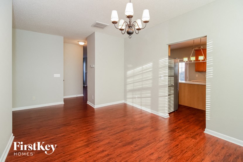 an empty living room with a wood floor and a chandelier