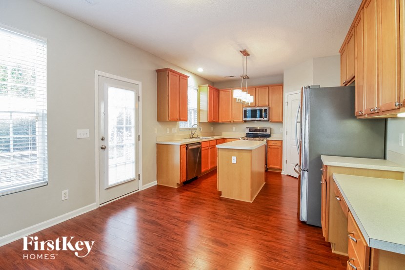 a kitchen with wood flooring and wooden cabinets and a stainless steel refrigerator