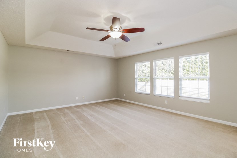 an empty living room with a ceiling fan and a window