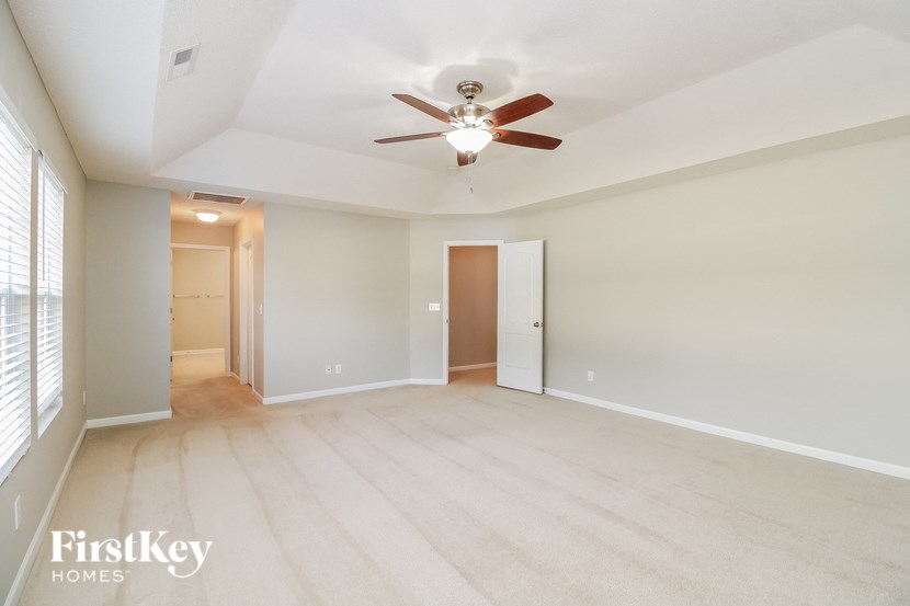 an empty living room with a ceiling fan and a window
