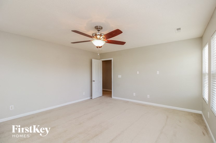 a spacious living room with white walls and a ceiling fan