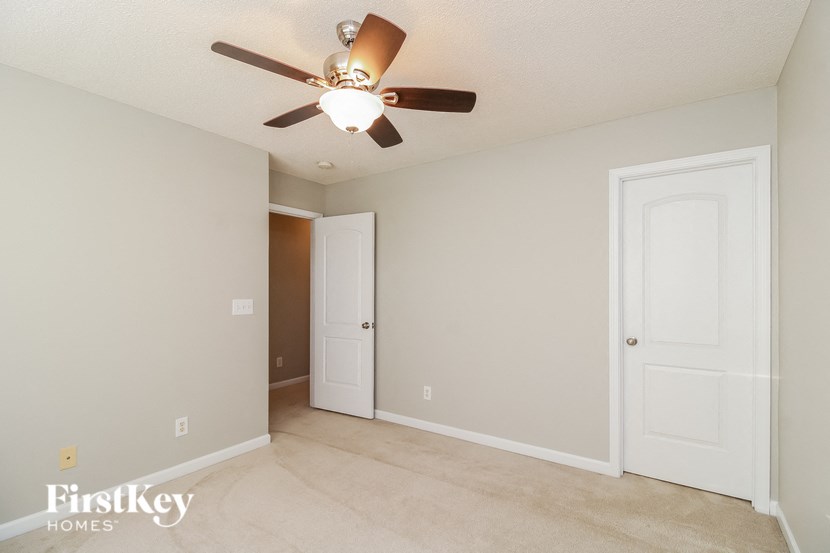a living room with a ceiling fan and a door to a closet