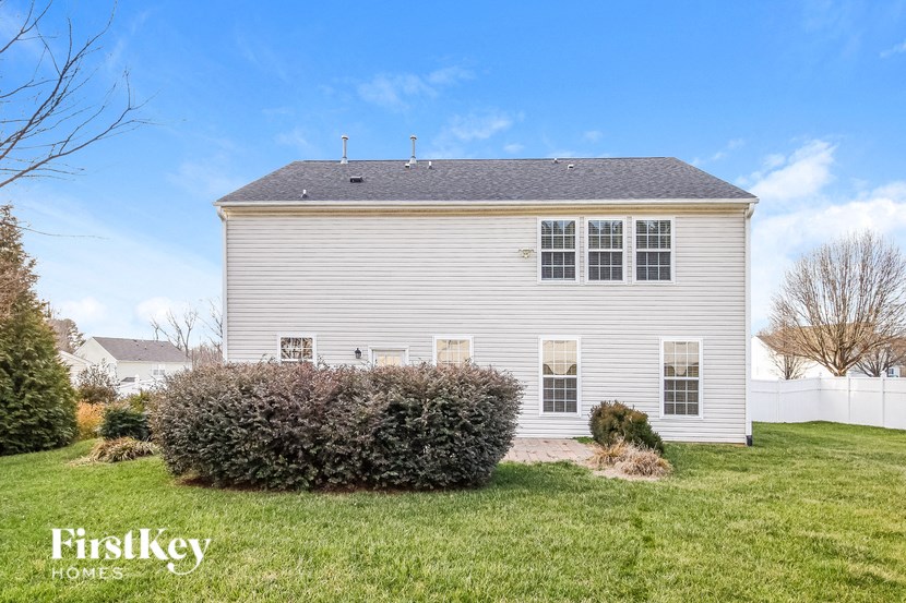 a white house with a yard and a hedge in front of it