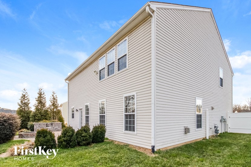 the outside of a white house with a grassy yard and trees