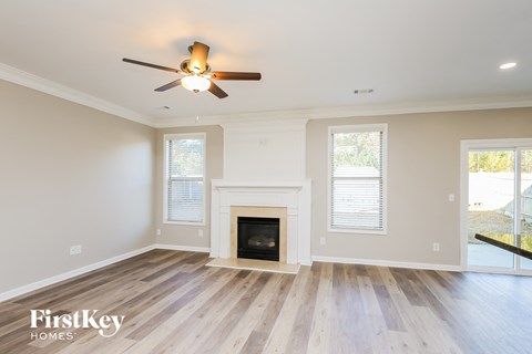 A spacious room with a fireplace and a ceiling fan.