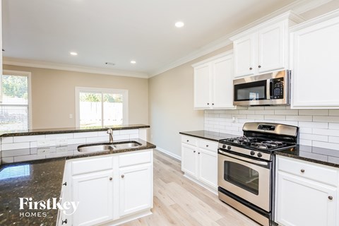 A kitchen with white cabinets and black countertops.