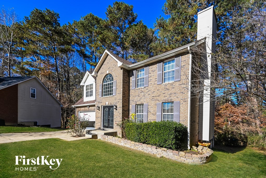 the front of a brick house with a yard and grass