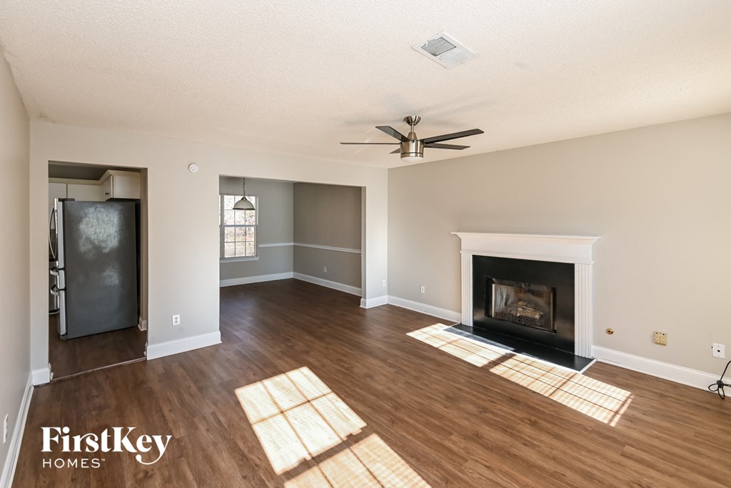 an empty living room with a fireplace and a ceiling fan