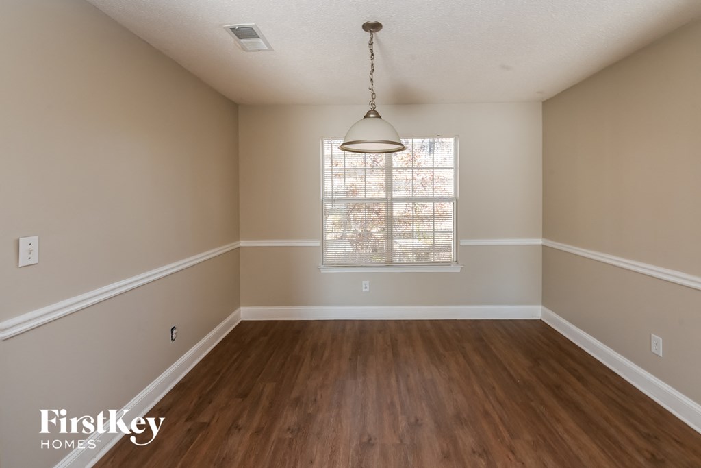 an empty dining room with wood floors and a window