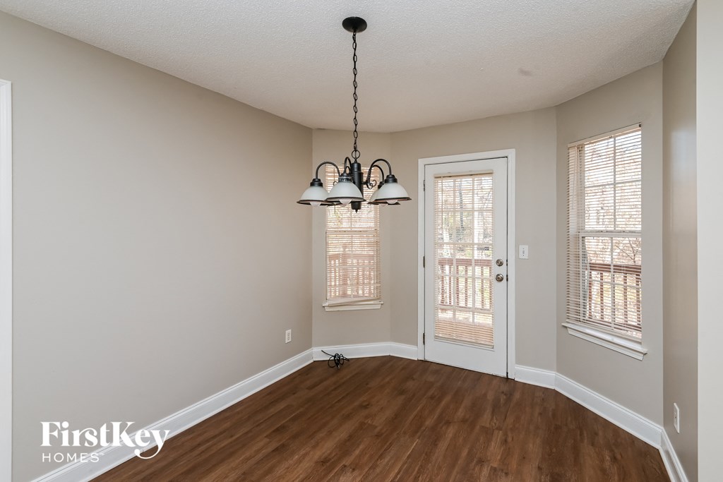 the living room of a house with a wooden floor and a chandelier