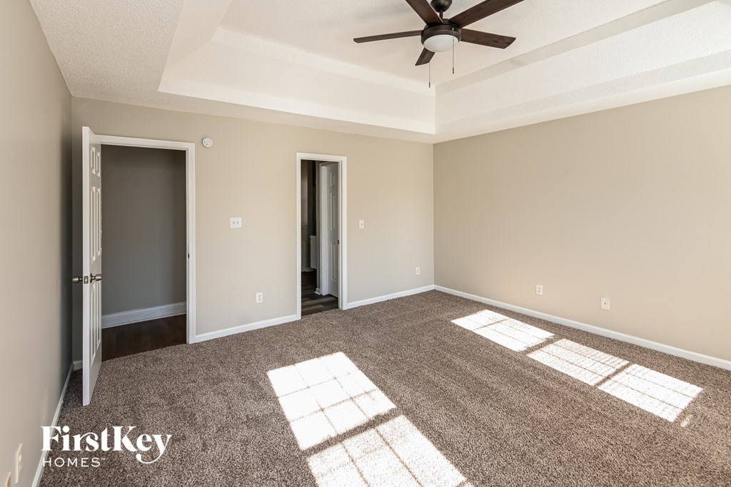 an empty living room with a ceiling fan and carpet