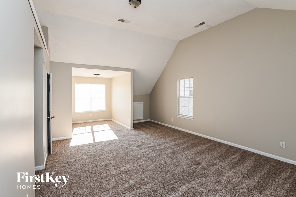 a spacious living room with carpet and a door to a bedroom