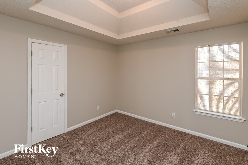 a bedroom with a white door and a carpeted floor