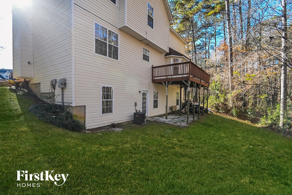 the back of a white house with a yard and a deck