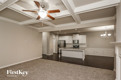 A spacious kitchen and living room with a ceiling fan and a chandelier.