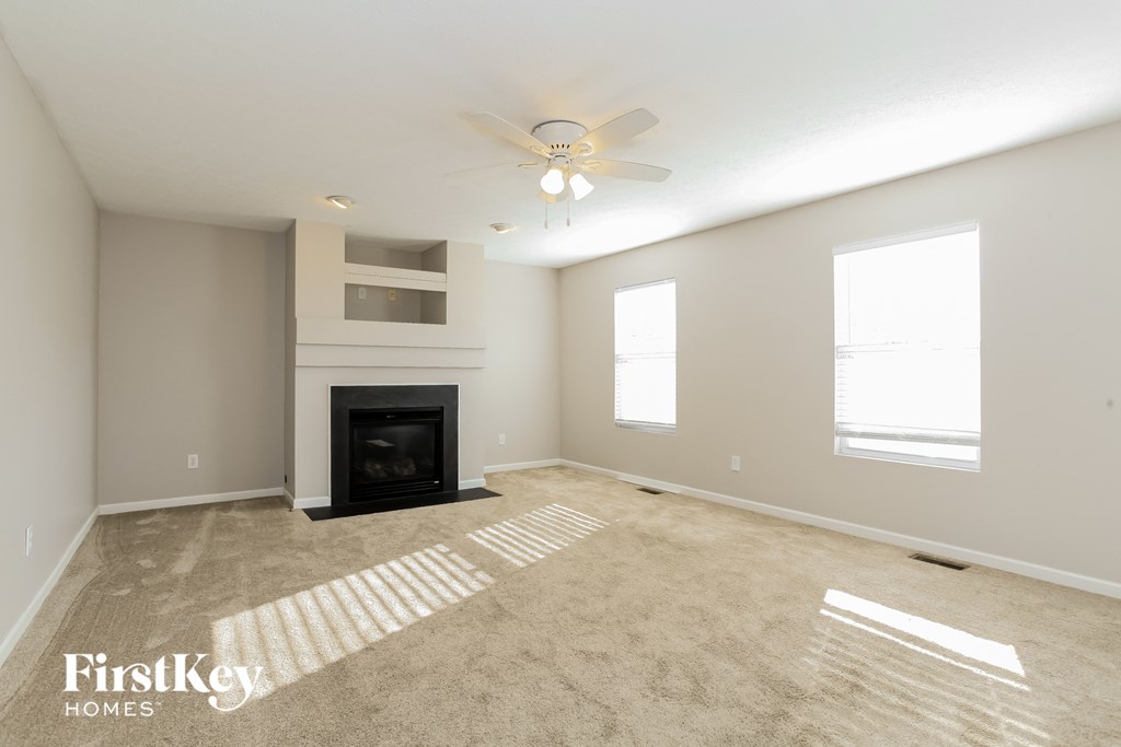 the spacious living room with fireplace and ceiling fan