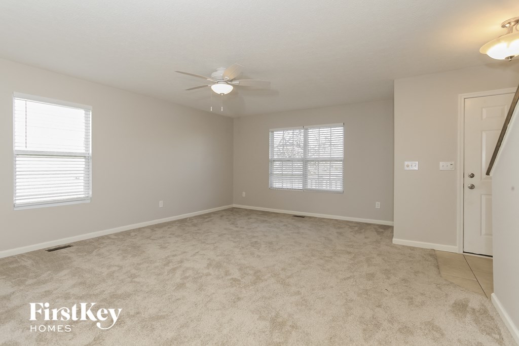 an empty living room with a ceiling fan and a door