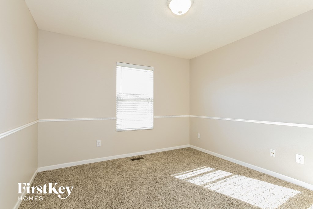 a bedroom with white walls and carpet and a window