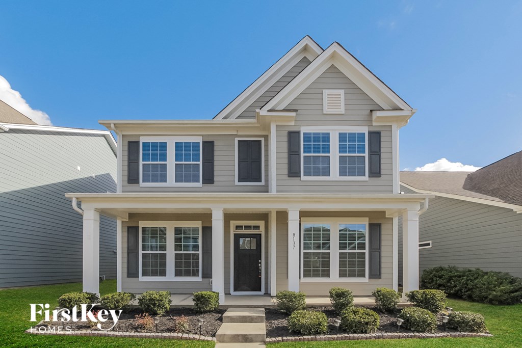A two-story house with a front porch and a black door.