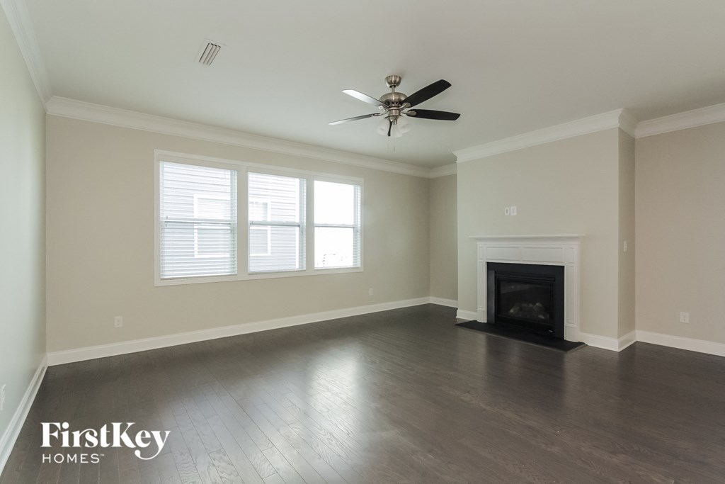 A spacious living room with a fireplace and a ceiling fan.