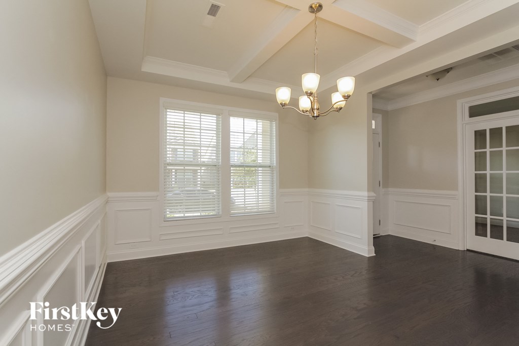 A well-lit room with a chandelier and a window with blinds.