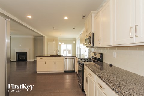 A kitchen with a granite counter top and white cabinets.