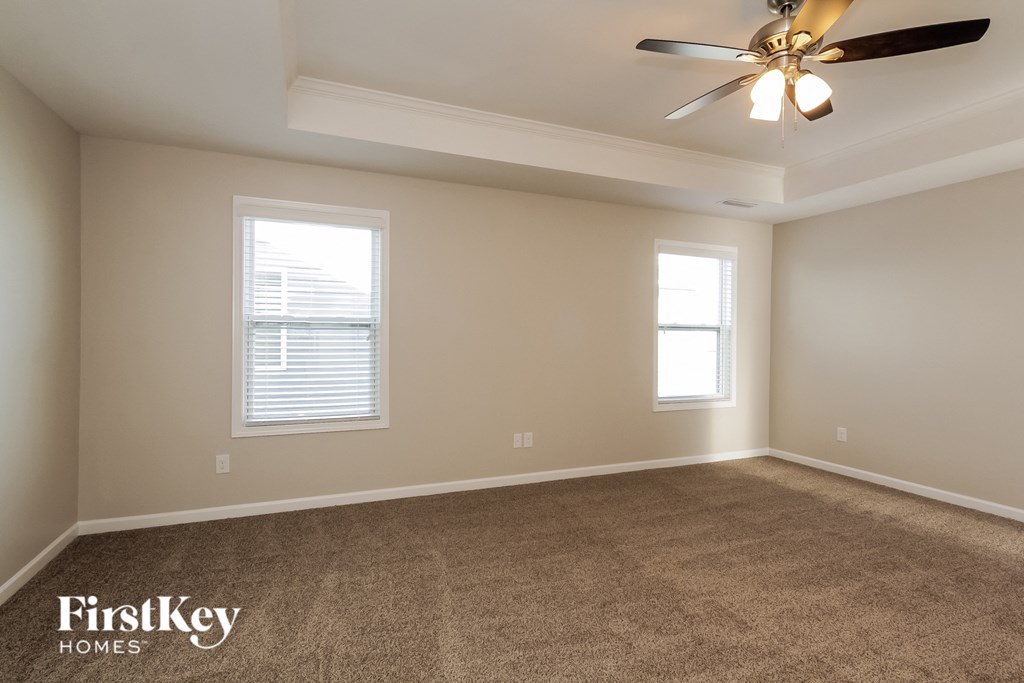 A room with a carpet floor and a ceiling fan.
