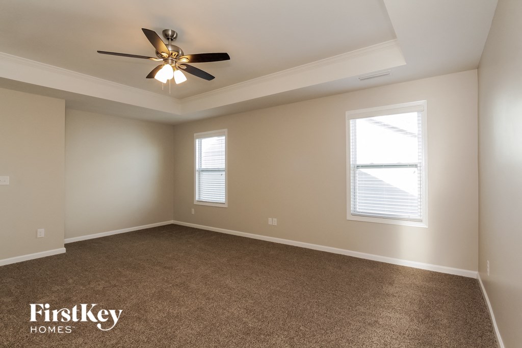 A room with a carpet floor and a ceiling fan.