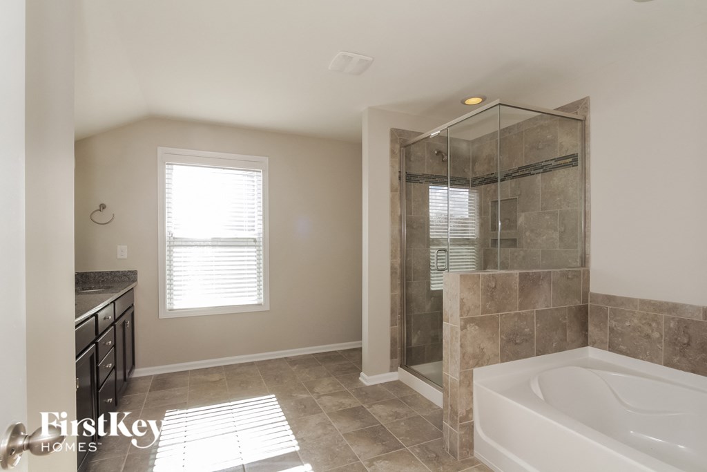 A bathroom with a tub, sink, and window.