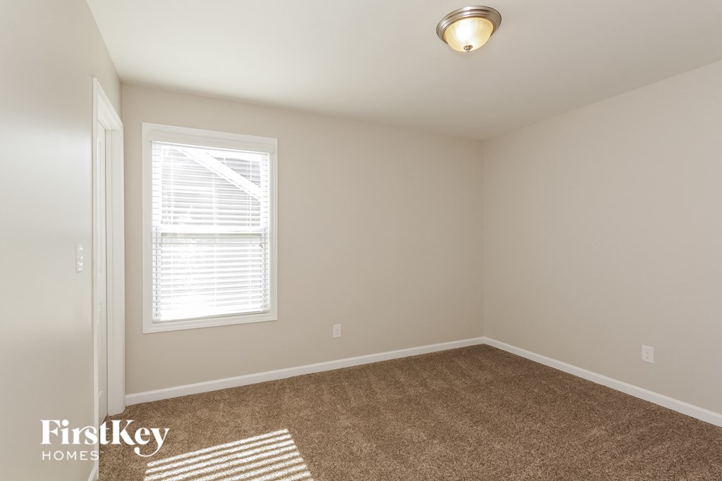 A room with a carpeted floor and a window with blinds.