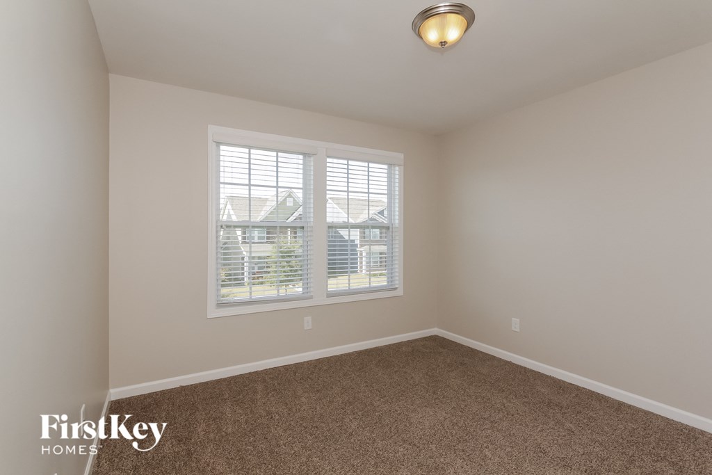 A room with a carpeted floor and a window with blinds.