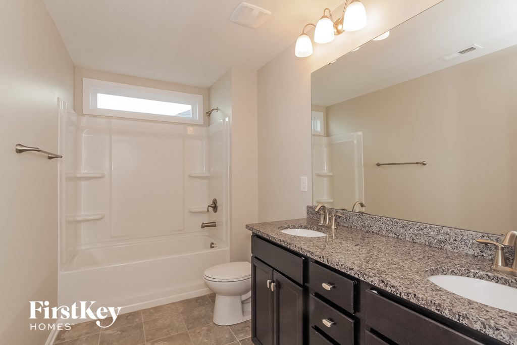 A bathroom with a toilet, sink, and mirror.