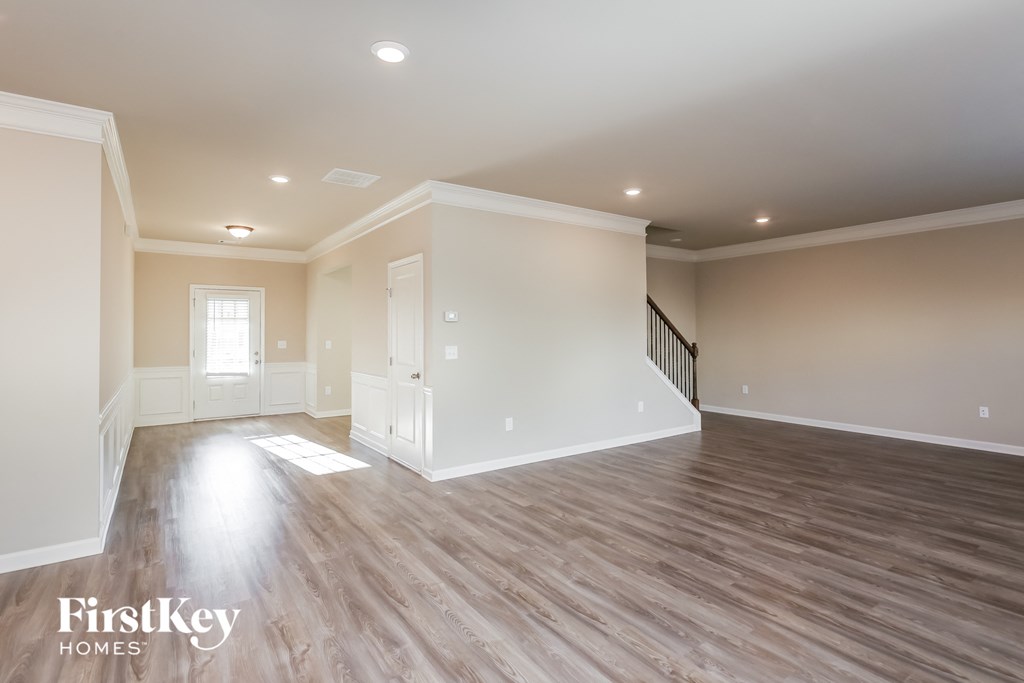 the spacious living room with hardwood flooring and white walls