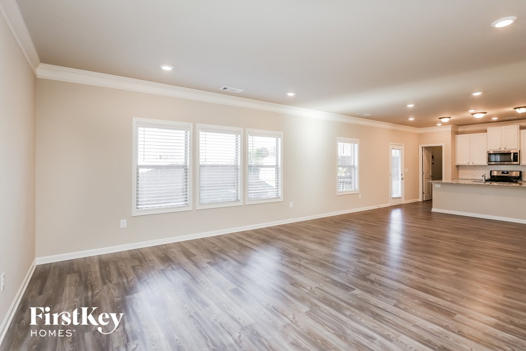 the living room and kitchen of a new home with a hardwood floor and windows