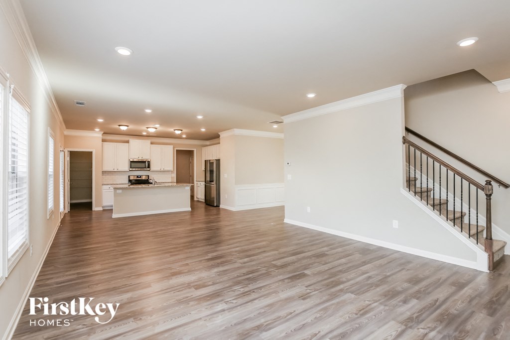 a renovated living room with a staircase and a kitchen